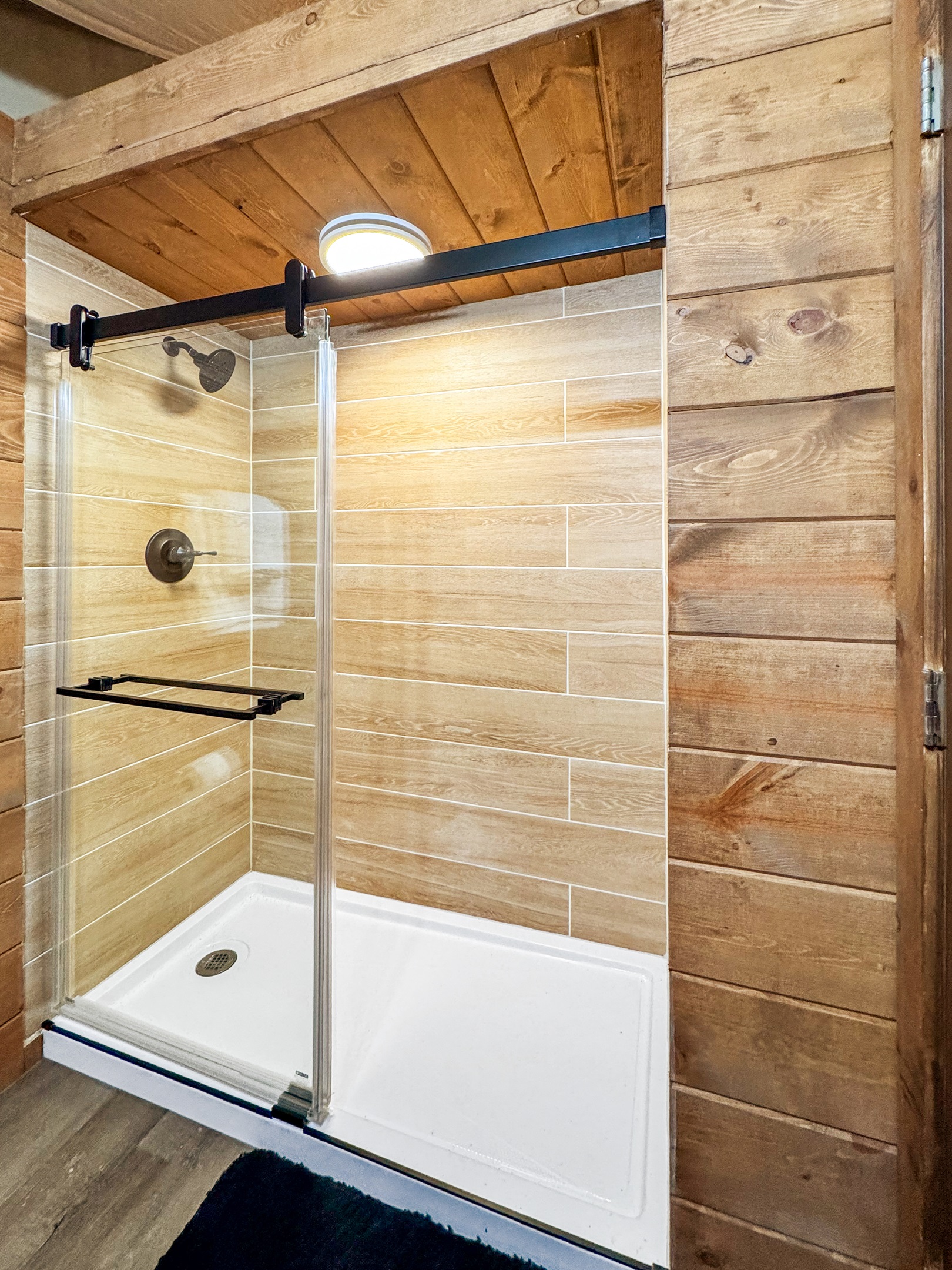 Enjoy a sleek glass shower with rustic wooden accents and stylish fixtures!
