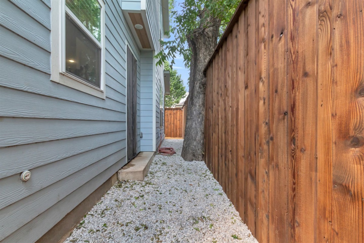 Side walkway with modern fencing and stone landscaping.