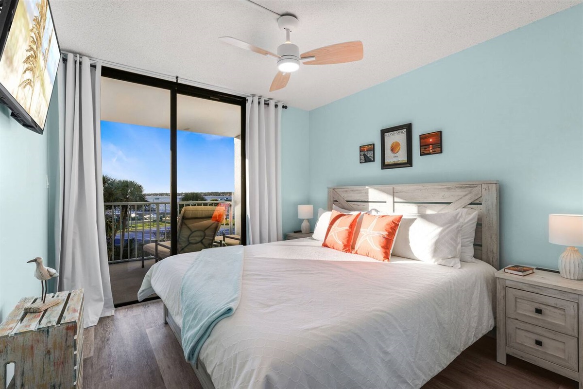 Cozy primary bedroom with private ensuite bath. King bed, access to balcony, Smart TV, nightstands with storage and charging stations. 