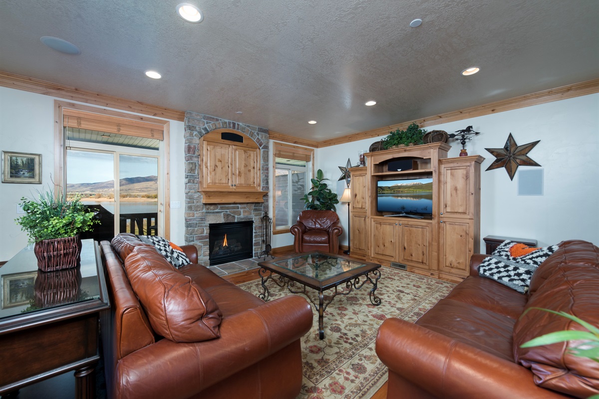 Comfortable living space with rustic charm, fireplace, and large windows framing the lake.