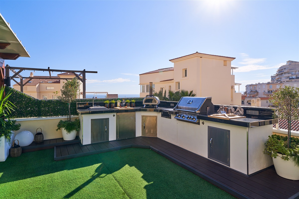 Cook with a view in the fully equipped outdoor kitchen featuring a BBQ, pizza oven, fridge, and sink. Dine al fresco under the open sky surrounded by soft lighting and fresh sea breeze.