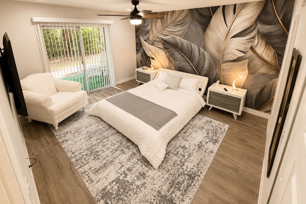 Spacious bedroom featuring a queen bed, reading chair, and direct patio access.