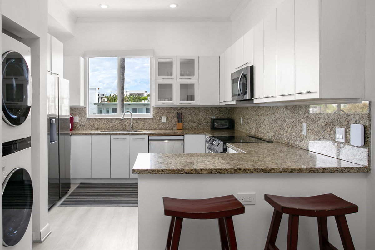 Chef's kitchen with dual-basin sink and breakfast counter. LG laundry tower right next to it.