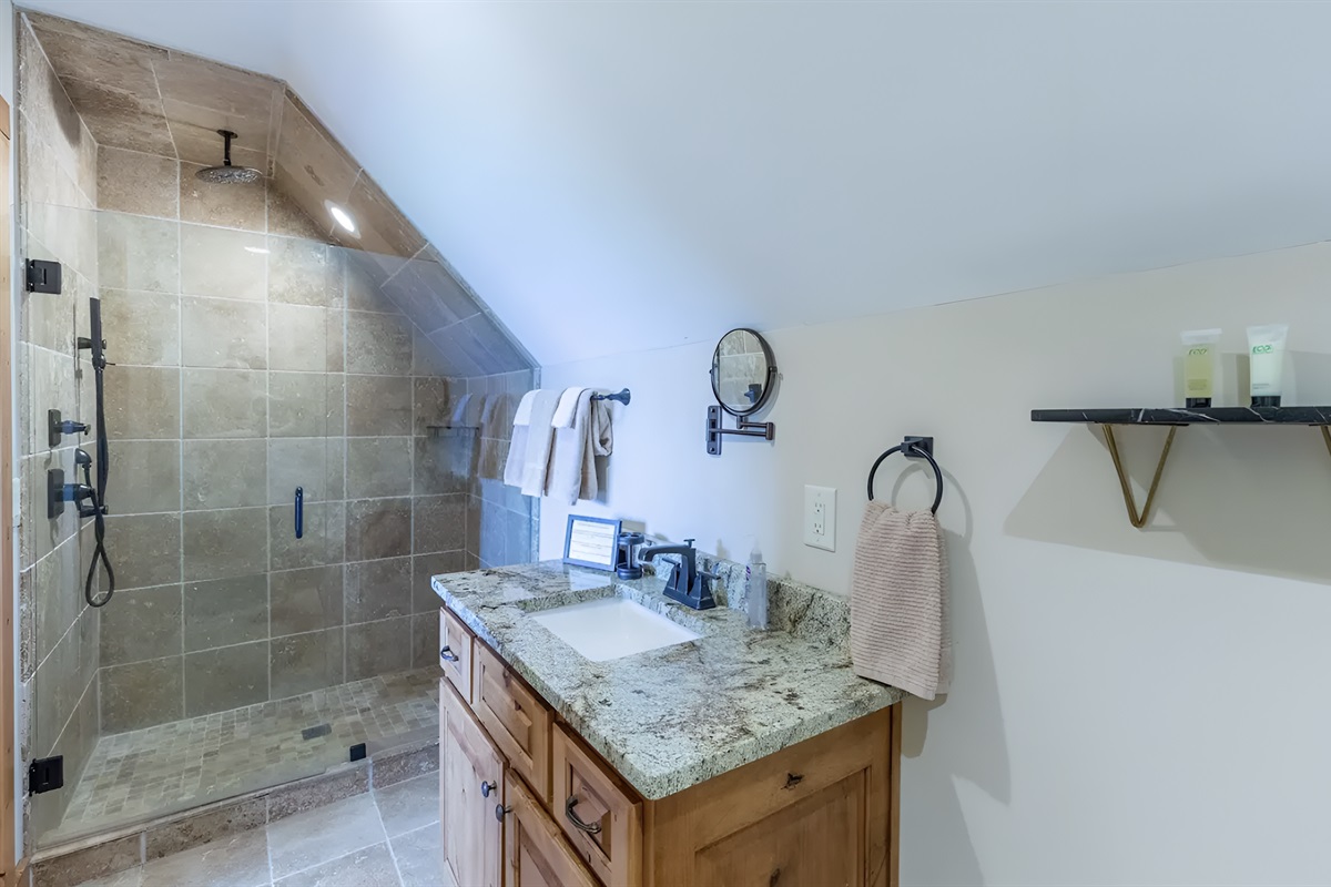 The upstairs queen bathroom is spacious, with a large shower and sink.