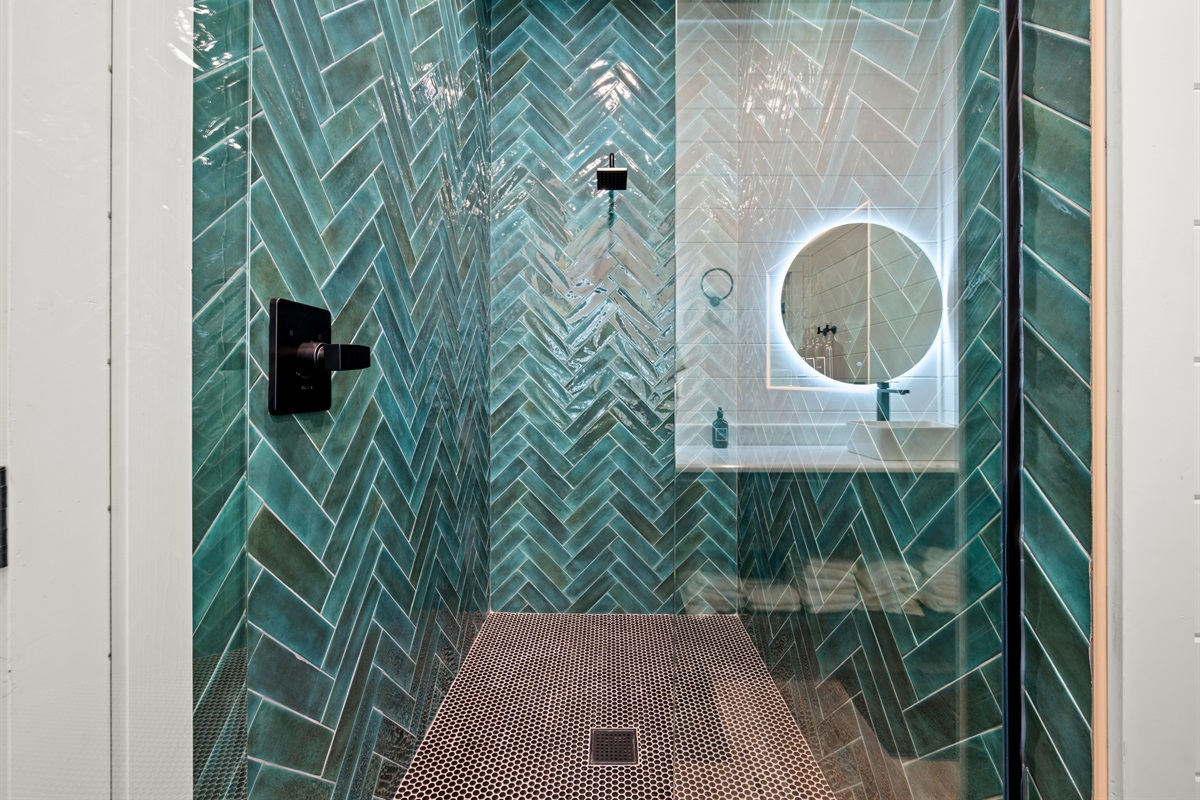 The walk-in shower features striking patterned tile and sleek fixtures that add a bold and modern touch to the space.