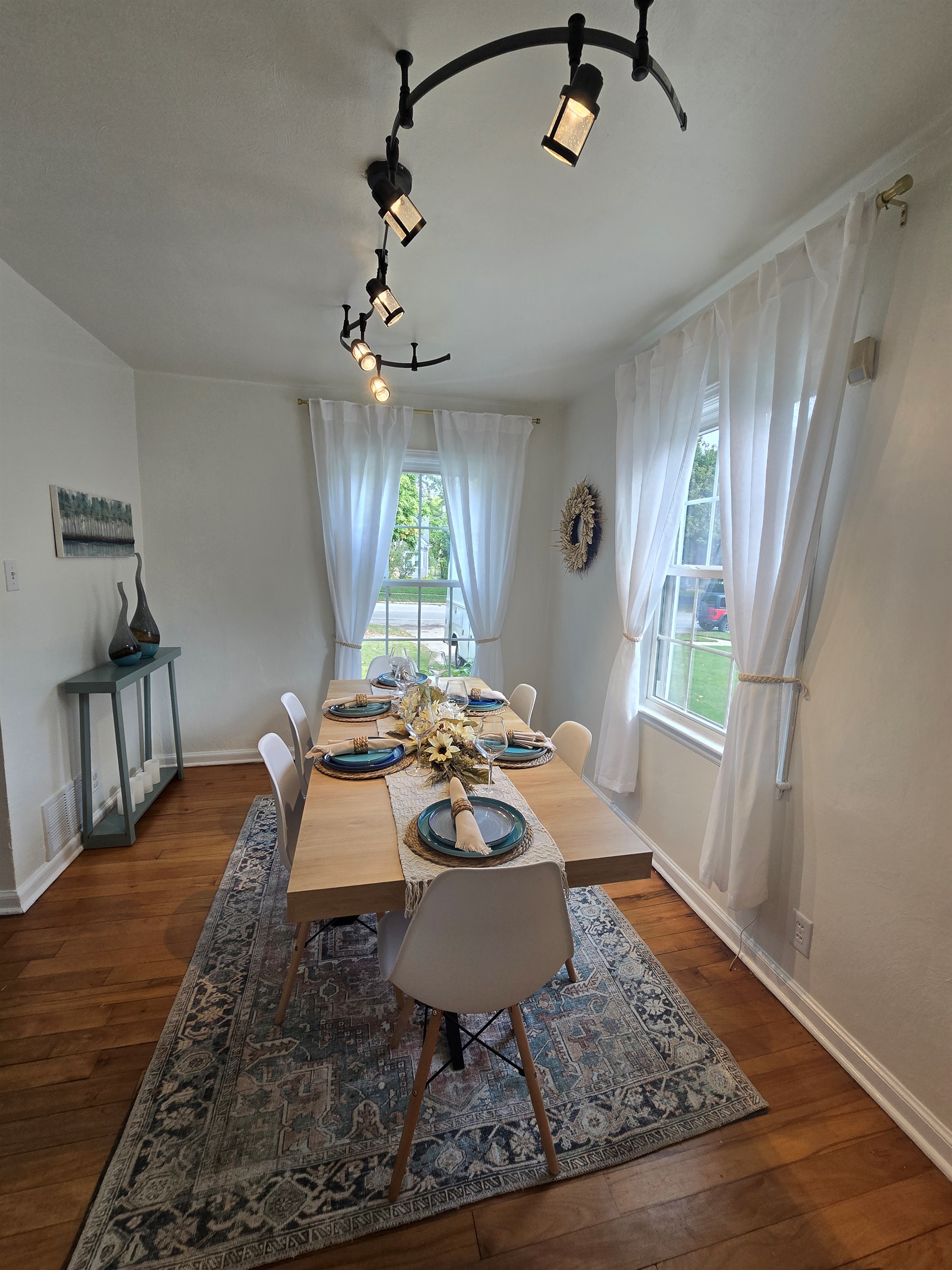 Fresh & Inviting Crisp white curtains, sleek chairs, and warm hardwood floors frame a table set for gathering