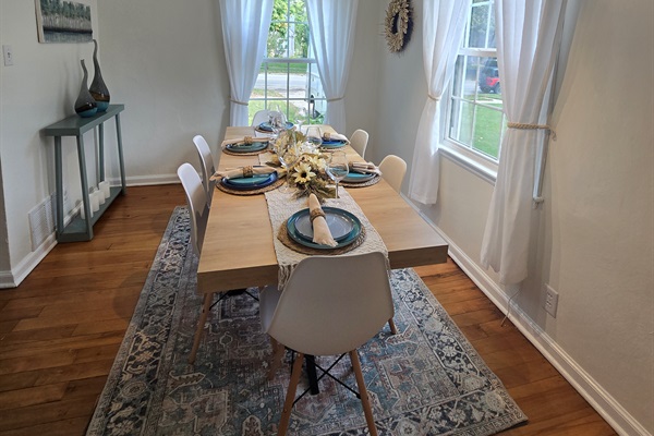 Fresh & Inviting Crisp white curtains, sleek chairs, and warm hardwood floors frame a table set for gathering