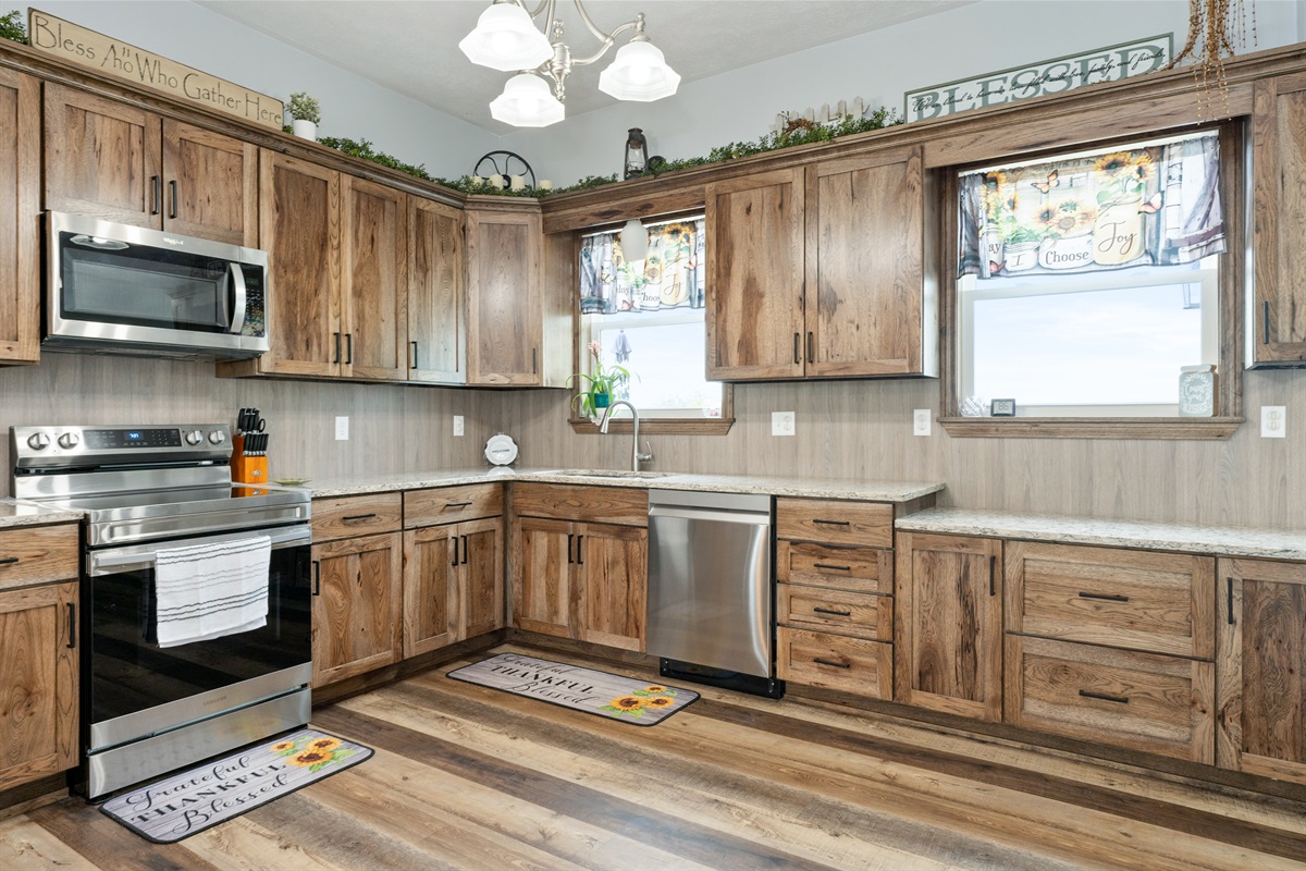Beautiful farmhouse-style kitchen with warm wood cabinetry, granite counters, and a spacious island with bar seating for four.