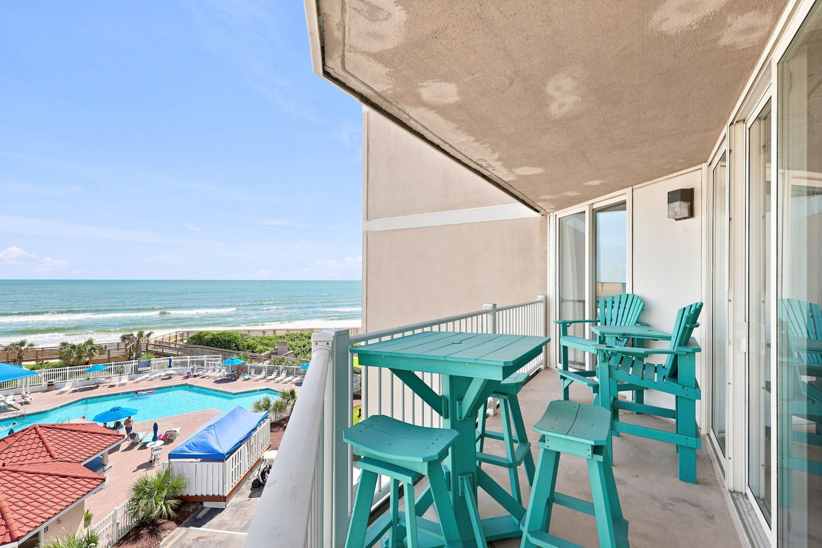 Relax outdoors on this spacious balcony furnished with seating, showcasing panoramic views of the resort setting and sea.