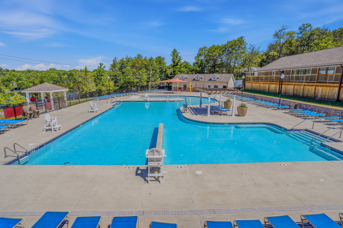 Community pool from the far end — open sky, lounge chairs, and full facility