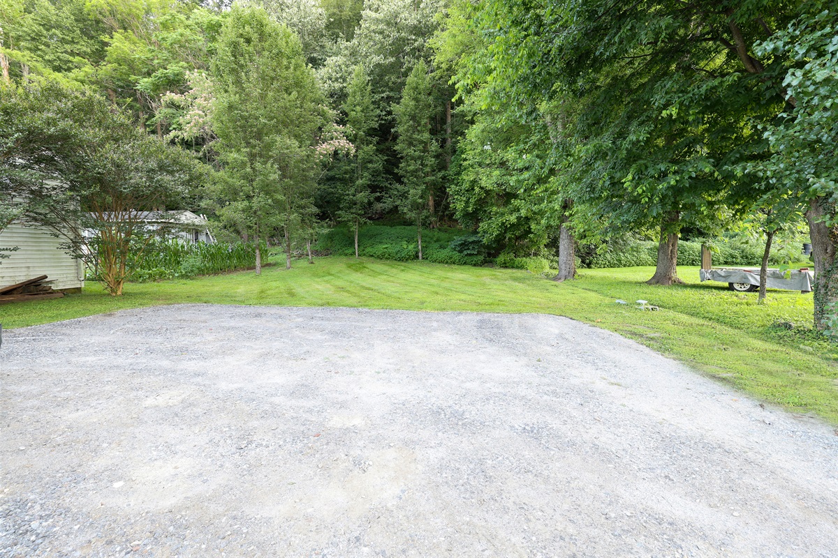 Large parking area behind the house with grassy backyard