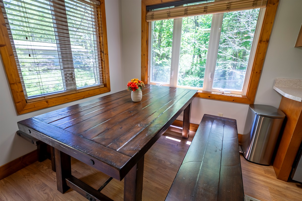This bright dining space features wraparound windows, bench seating, and tranquil views of Yellow Creek just beyond.
