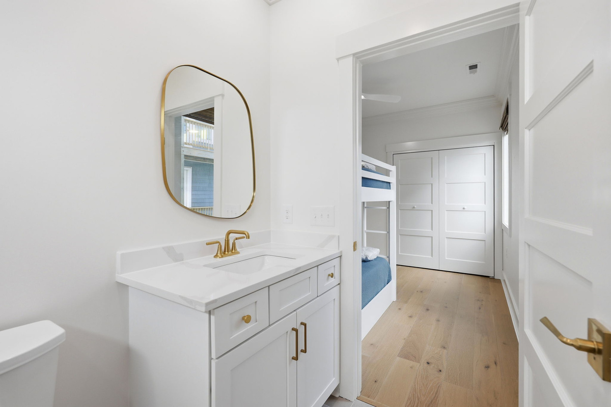 Modern bathroom vanity with white cabinetry, gold hardware, and clean minimalist design