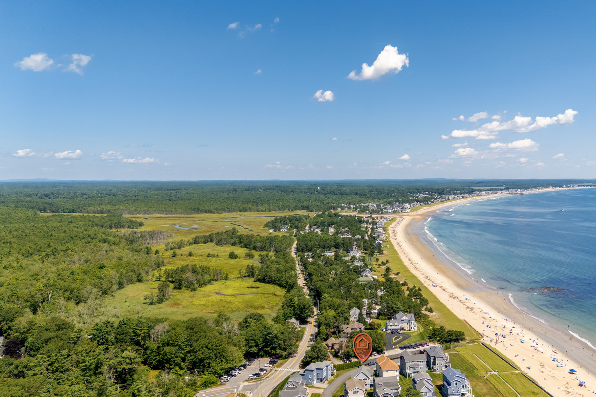 A spectacular bird's-eye view showcases the sweeping coastline, sandy beach, and coastal neighborhood below.