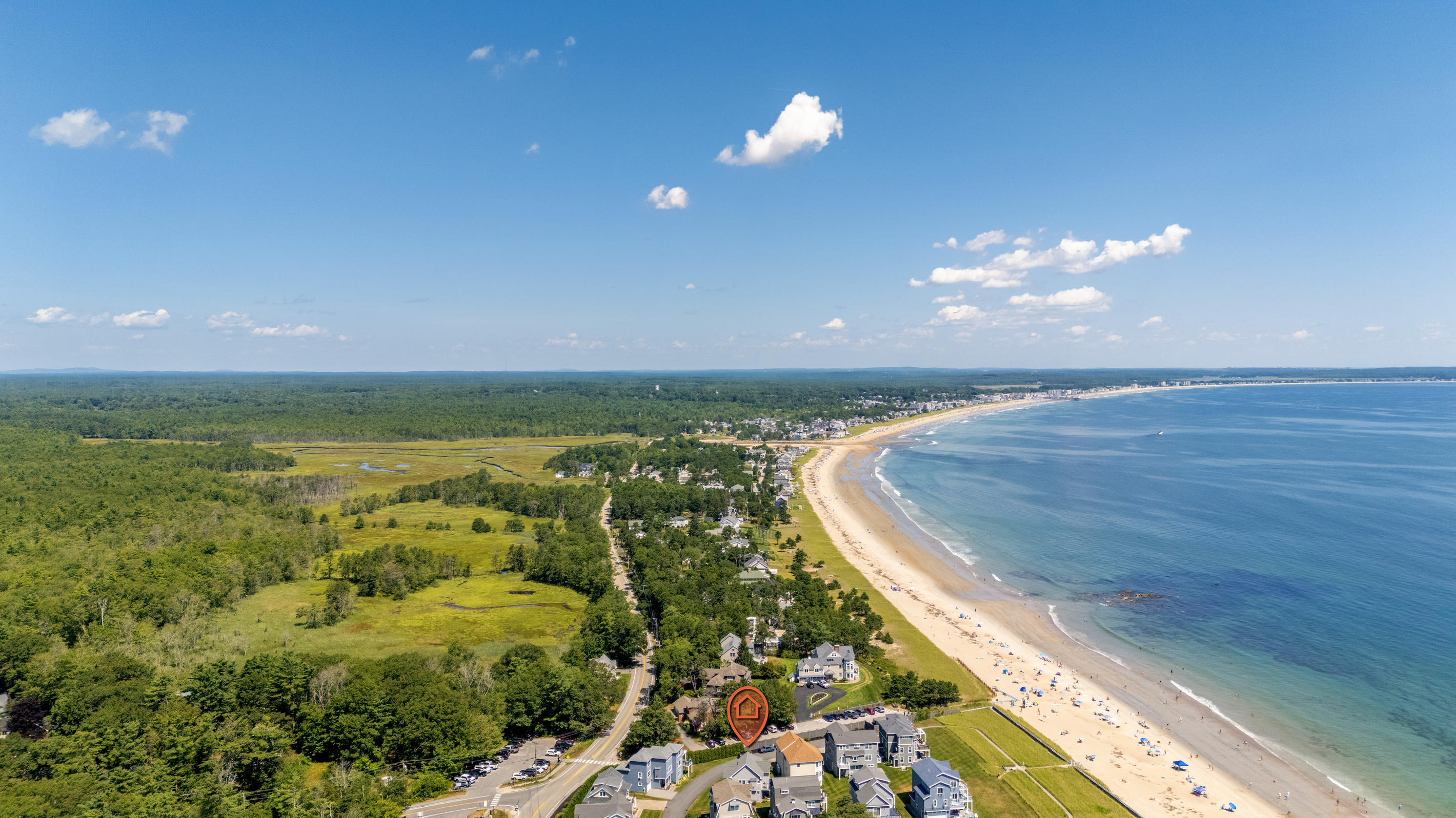 A spectacular bird's-eye view showcases the sweeping coastline, sandy beach, and coastal neighborhood below.