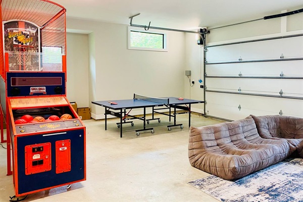 Garage game room complete with Super Shot arcade basketball game, table tennis table (equipment included), card games, kids toys, and lounger chairs.