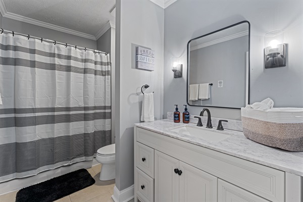 Modern full bathroom with fresh linens and a stocked shower/tub combo.