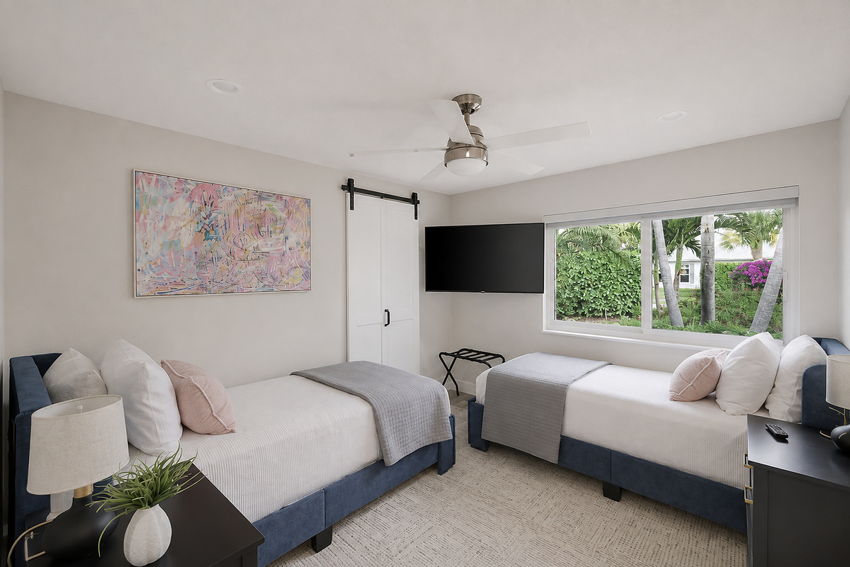 A bright twin bedroom gives kids, friends, or family members their own comfortable space with a TV, ceiling fan, and garden view.