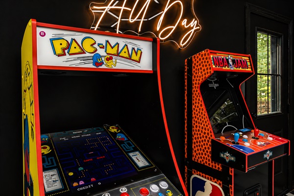 Pac-Man and NBA Jam standing at attention under the neon sign — the classics are here in full size and fully playable.