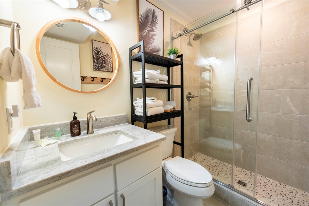 Stylish bathroom oasis with sleek design, glass shower, and cozy details.