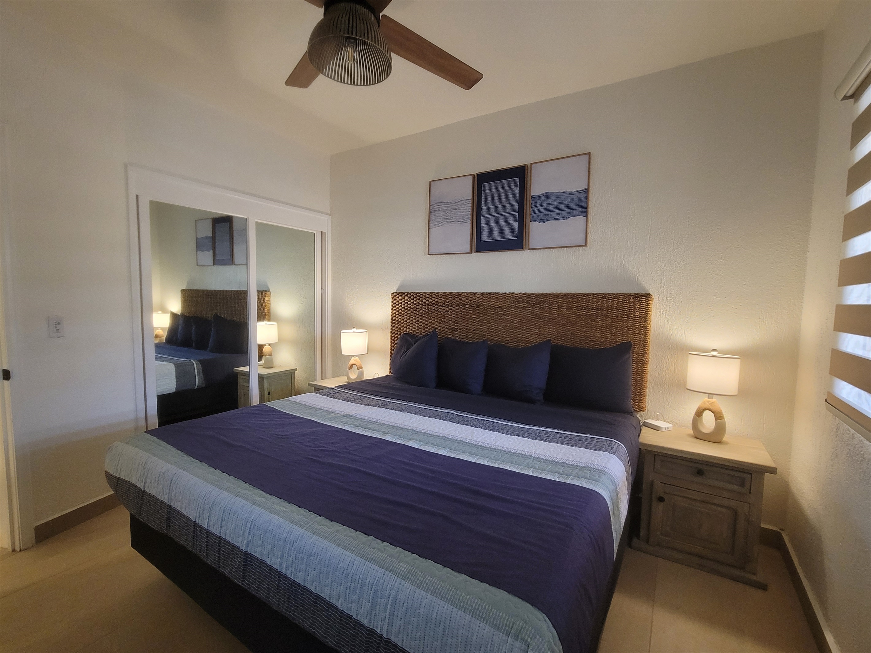 Guest bedroom featuring a king bed, two nightstands, lamps, dresser, closet and a Roku TV.