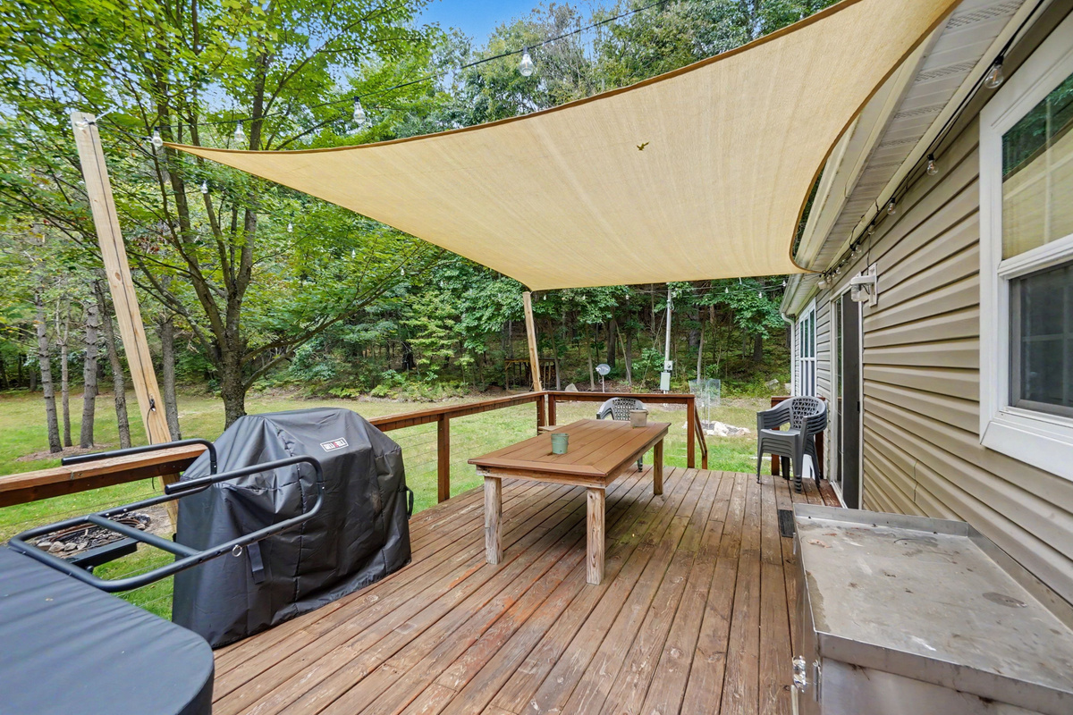 Deck with hot tub, gas grill, patio table and chairs.