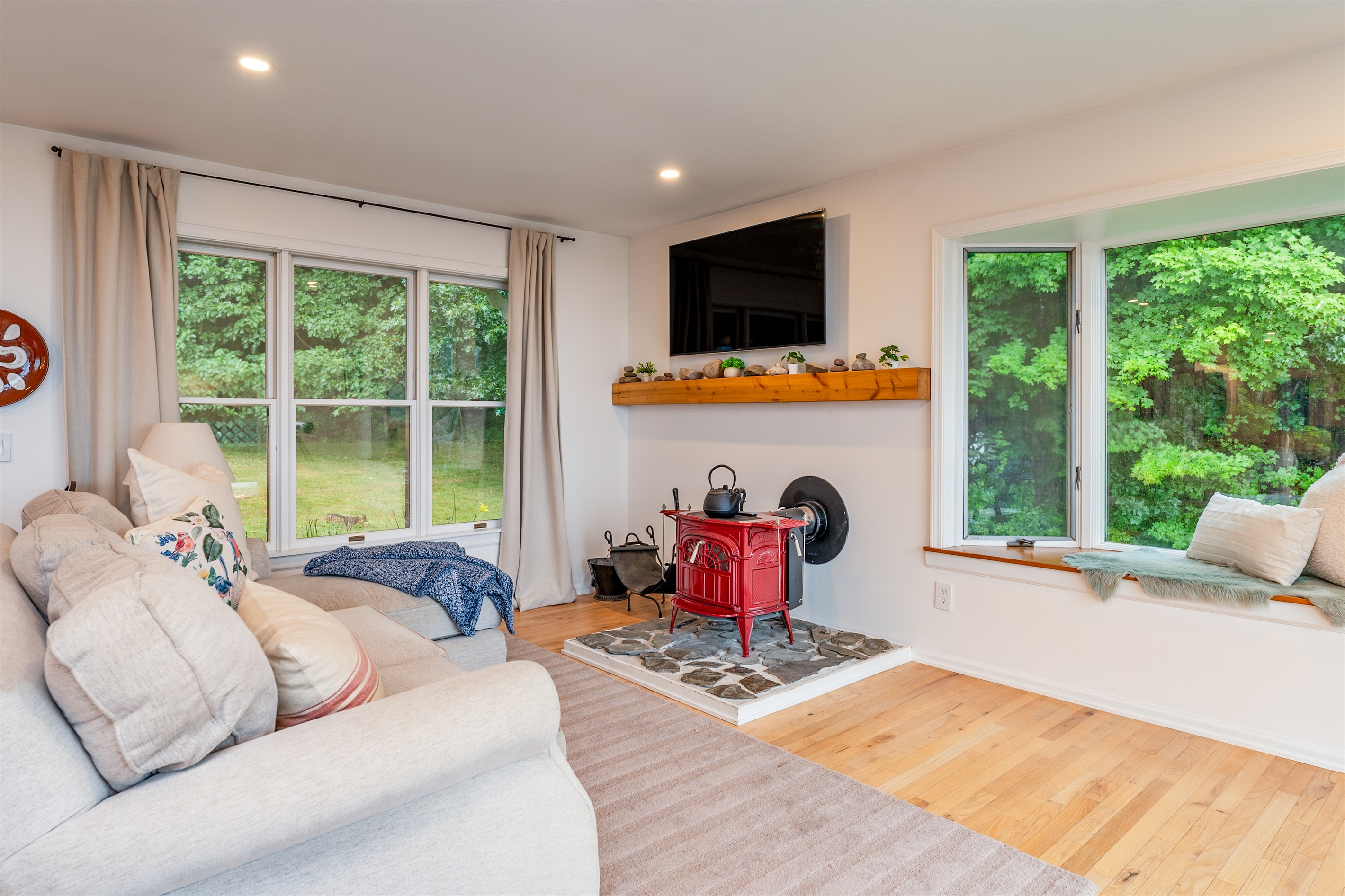 Bright and airy living space with large windows, wood floors, and forest views—relax in style with comfort all around