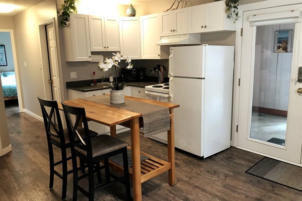 Fully equipped and stocked kitchen with apartment size fridge, stove, microwave, blender, slow cooker, cookware, and tableware. 