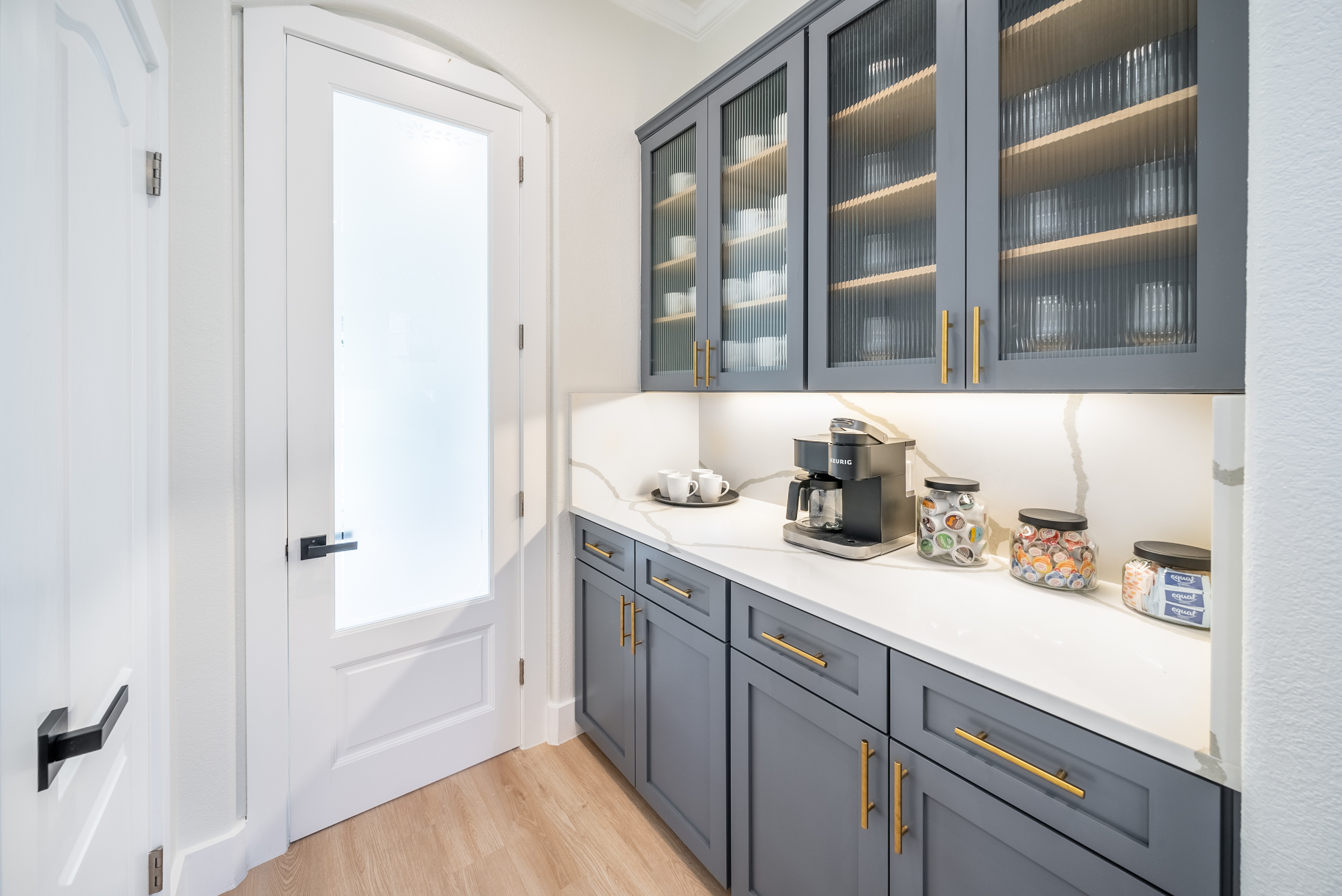 Well-stocked pantry with glass-front cabinetry, tucked just off the kitchen.