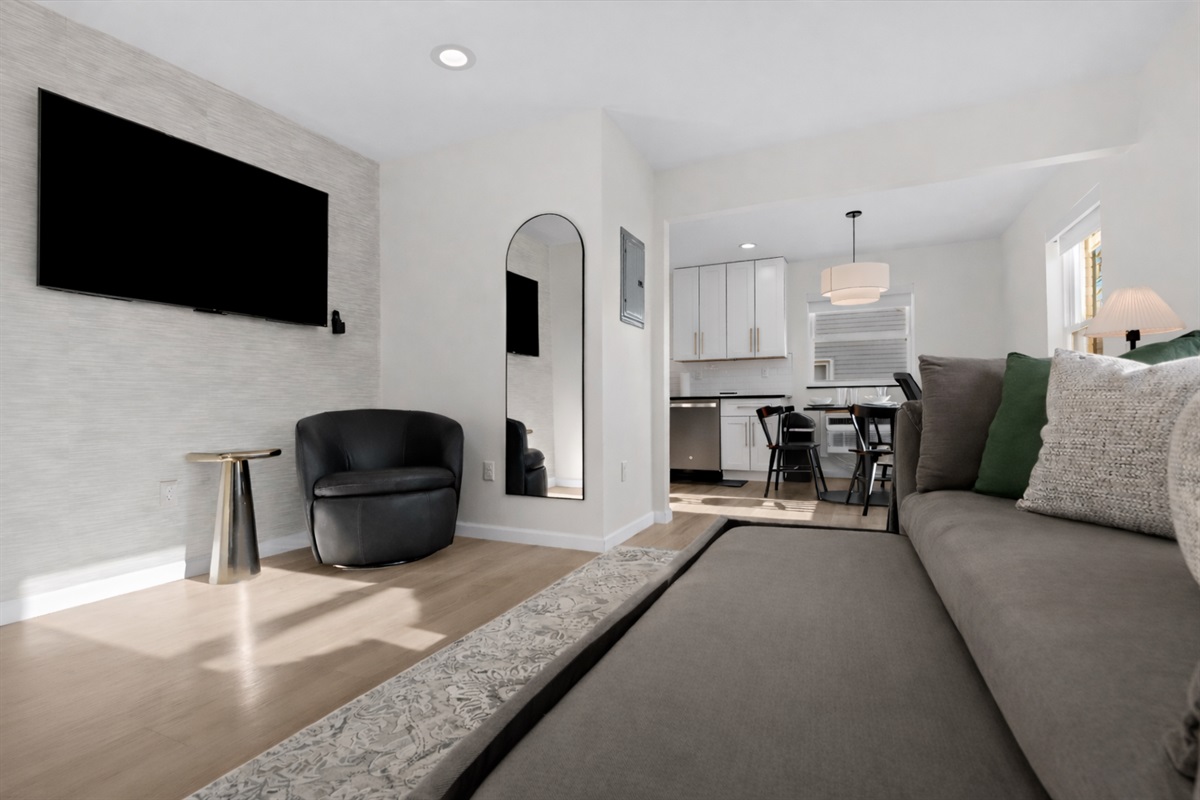 Open, modern living space with a pull-out sofa, smart TV, and stylish seating—perfect for relaxing, entertaining, or hosting additional guests.