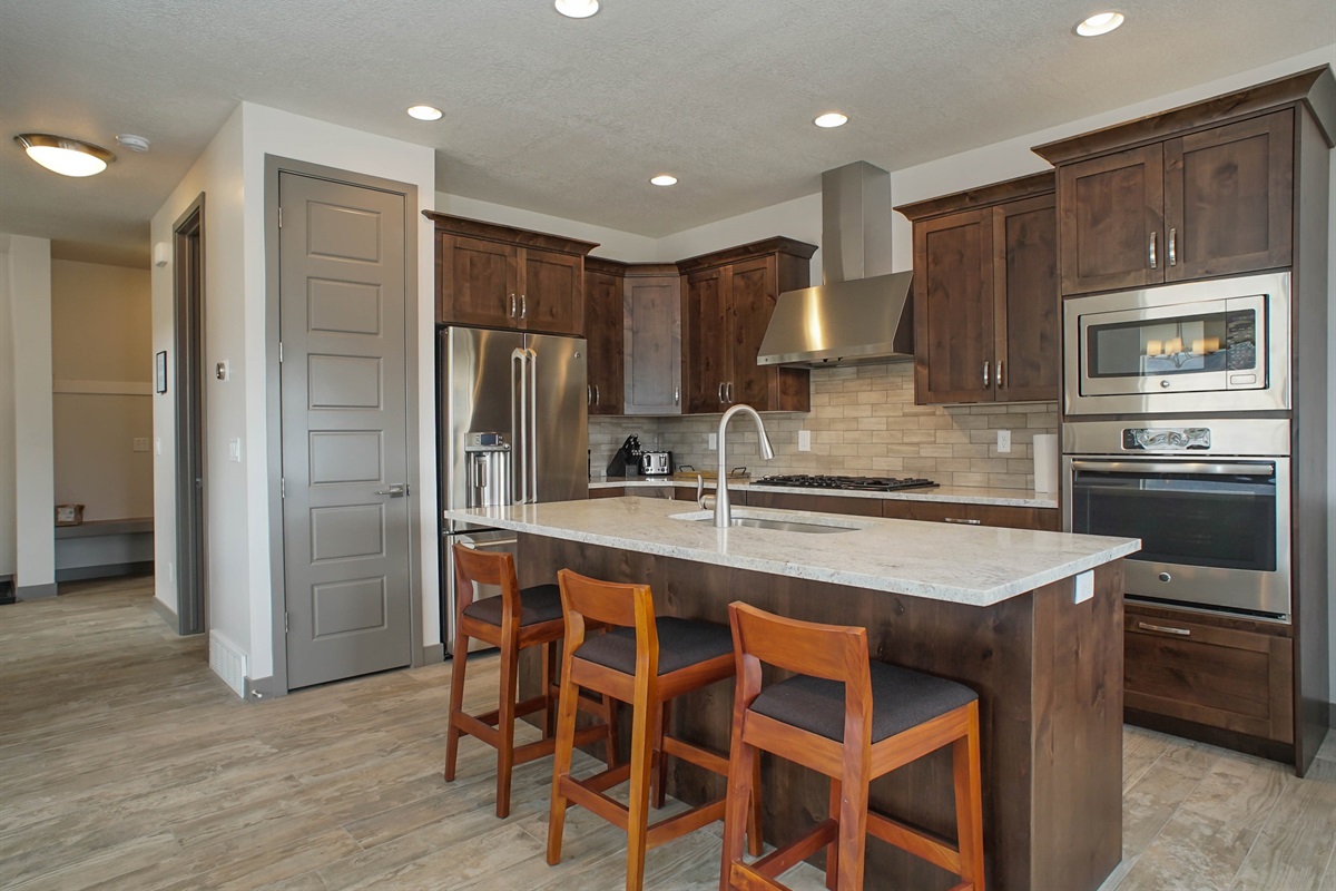 A beautifully designed kitchen featuring a large island, sleek appliances, and warm wood cabinetry—ideal for both entertaining and everyday luxury.