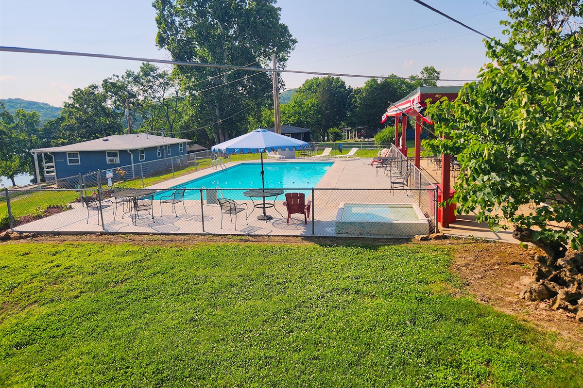 Another view of the pool shows the tables, umbrellas, & lounge chairs. The surface was freshly painted with a heat reducing paint for more comfort!