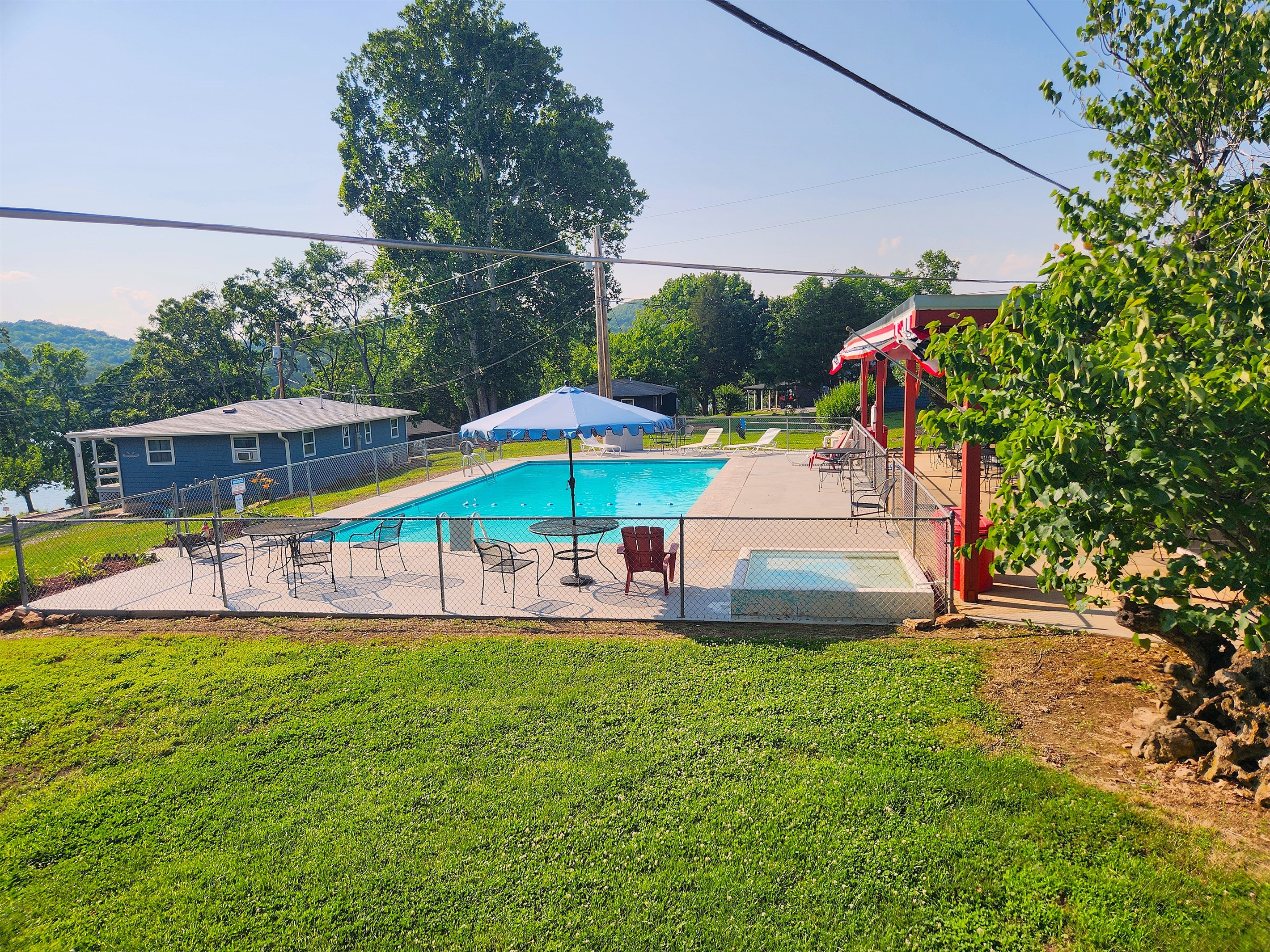 Another view of the pool shows the tables, umbrellas, & lounge chairs. The surface was freshly painted with a heat reducing paint for more comfort!