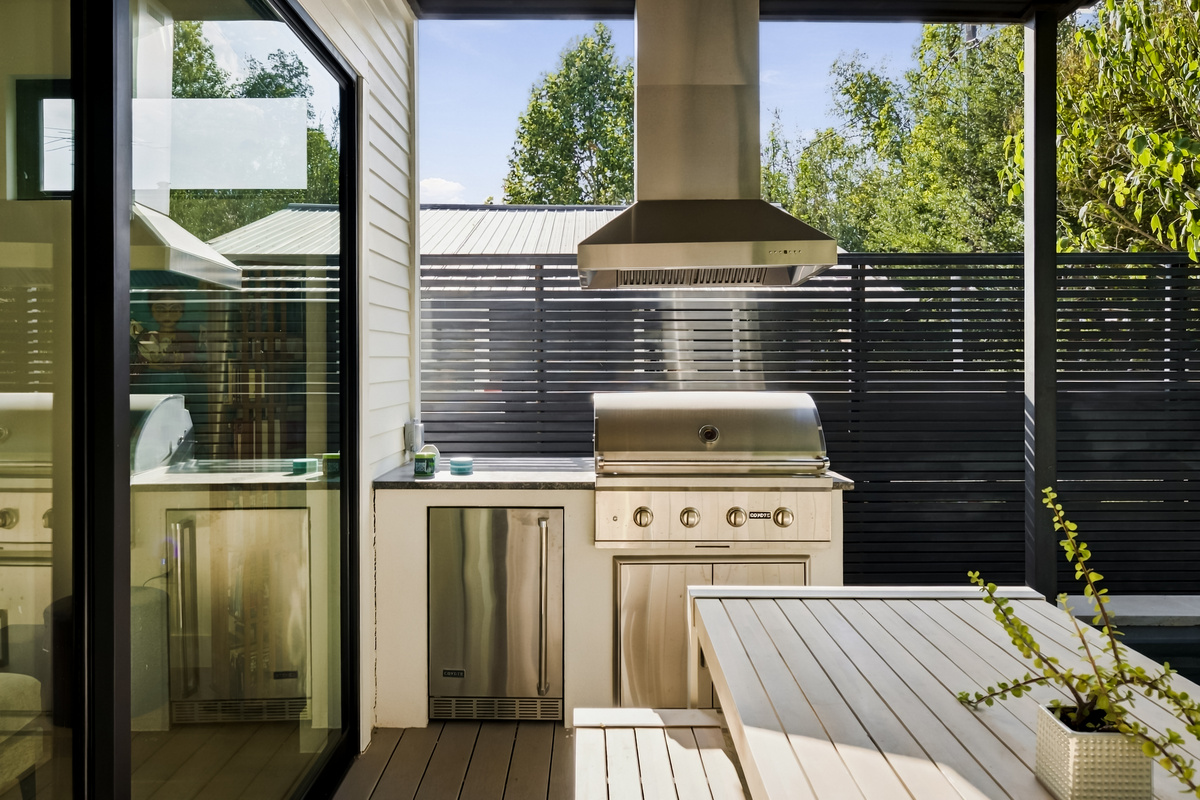 Covered outdoor dining with a built-in Coyote grill and mini fridge.