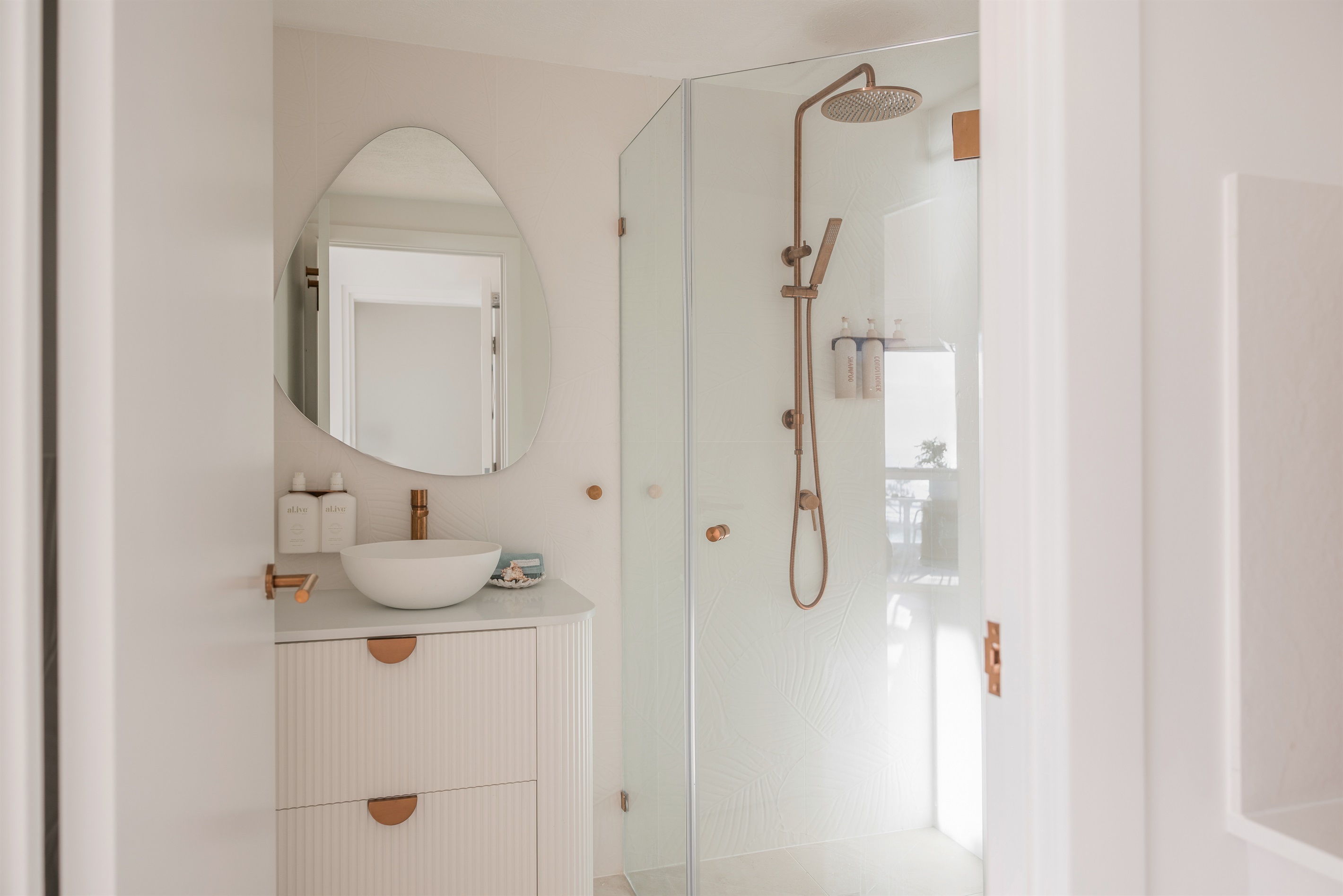 Newly renovated studio bathroom with rainfall shower, brushed-copper fixtures & complimentary premium toiletries.