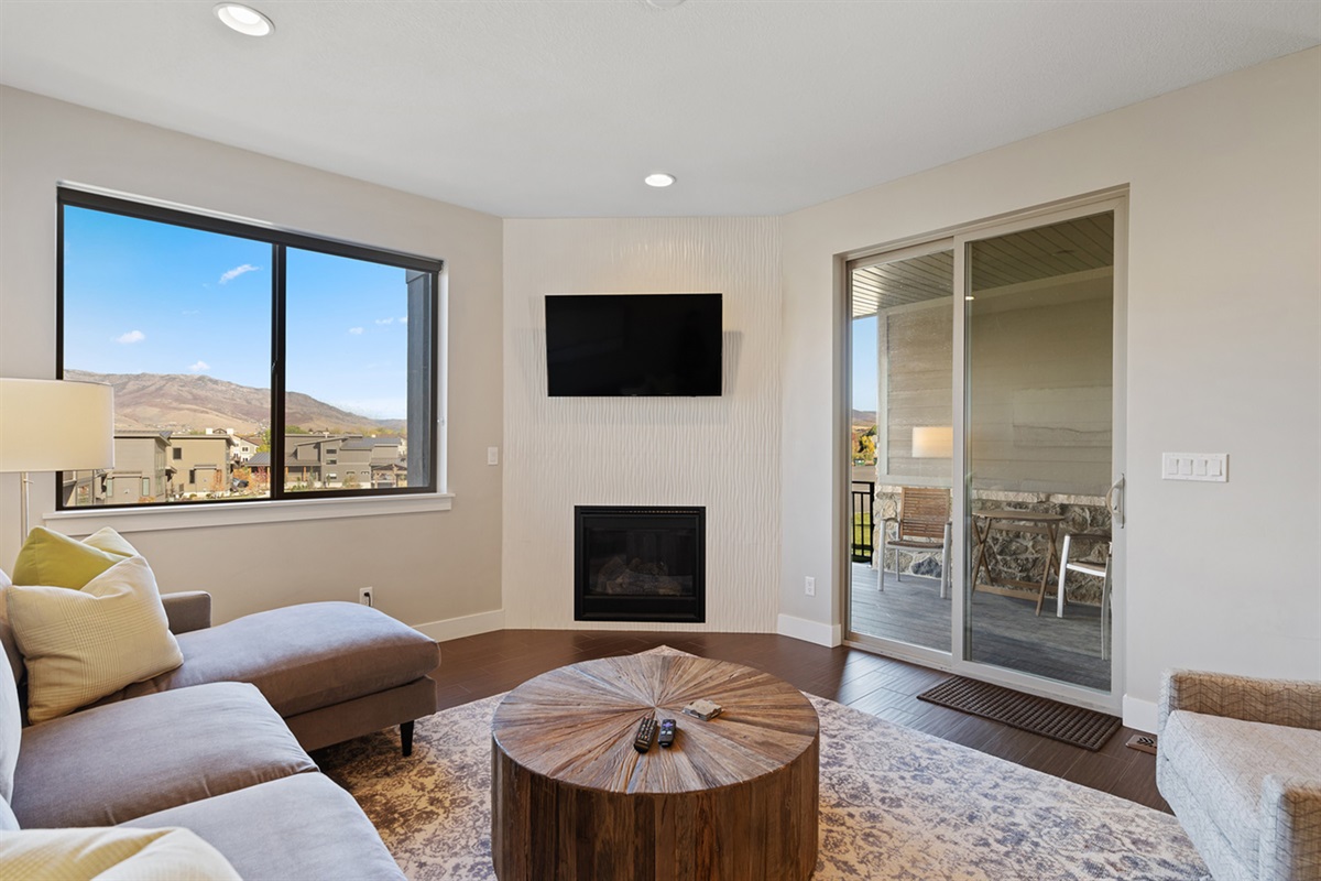 The living room has mountain views, a fireplace, TV, and access to the outdoor patio.