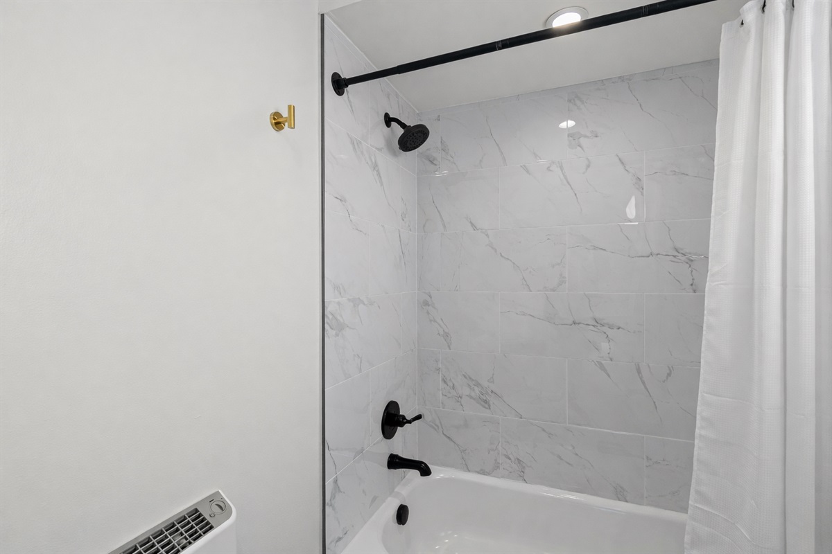 Sleek tub-shower combo with modern tile, matte black fixtures, and a clean, spa-like feel—perfect for unwinding after a long day.