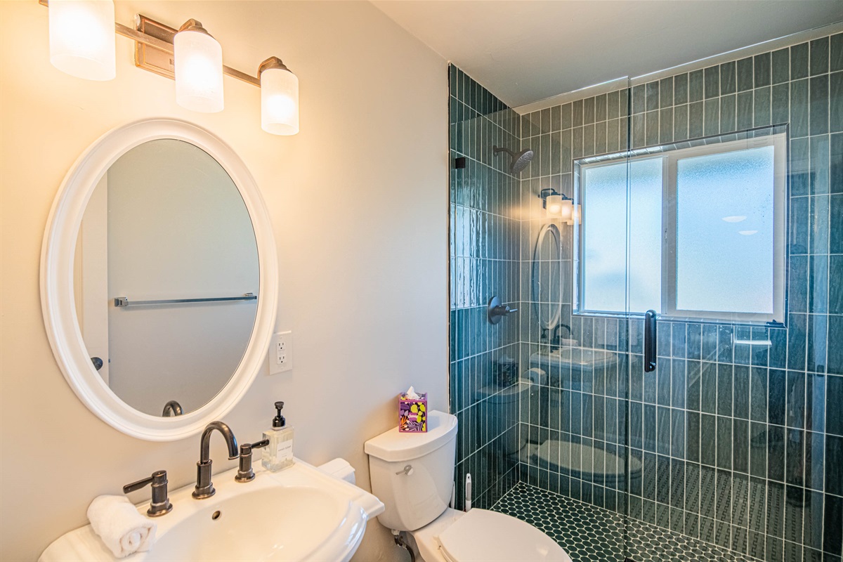 Stylish bathroom with updated vanity, modern lighting, and tiled shower — combining comfort and clean design.