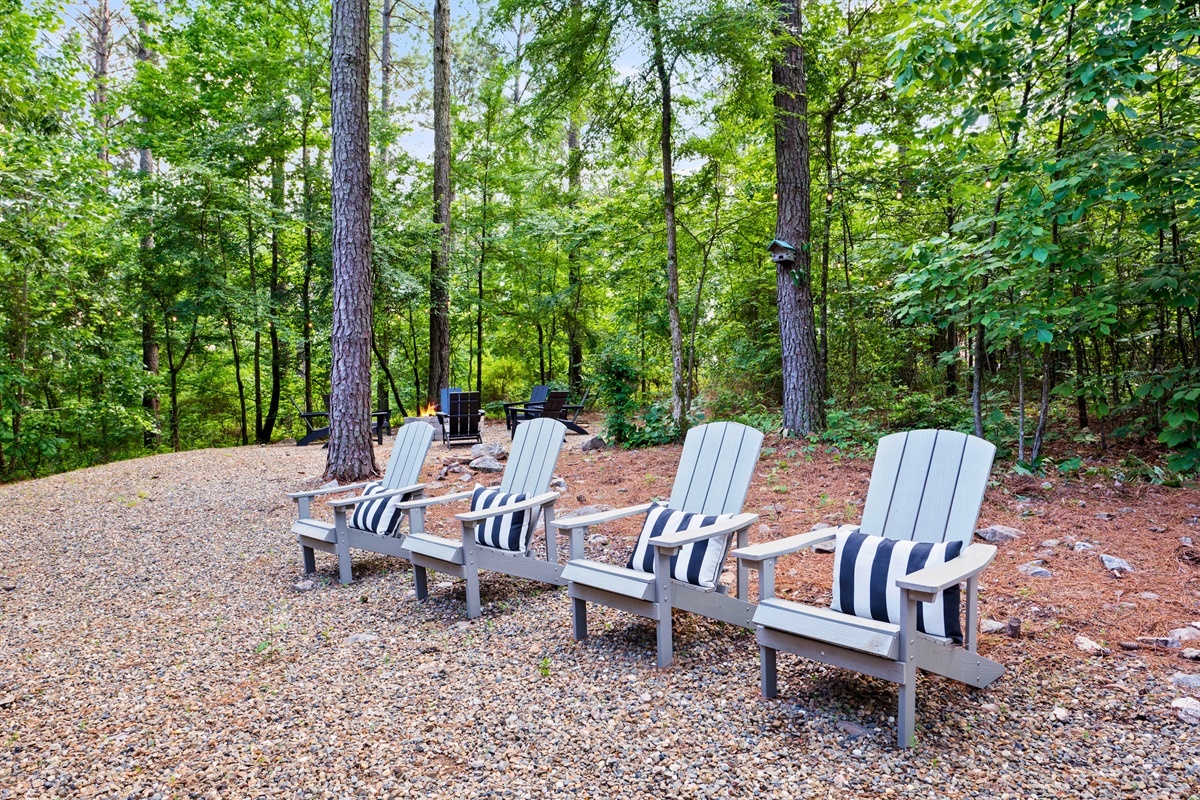 A tranquil seating area with four Adirondack chairs, adorned with striped cushions,
