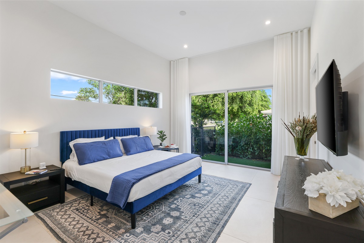 Main-level primary suite – king bed, private pool access, 65” Smart TV, and spa-style ensuite bath.