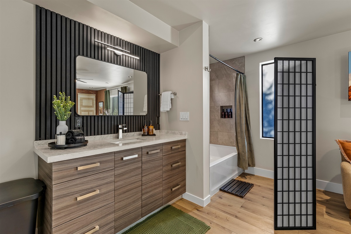 Modern ensuite bathroom at the guesthouse featuring a spacious vanity, tub/shower combo, and thoughtfully stocked essentials.