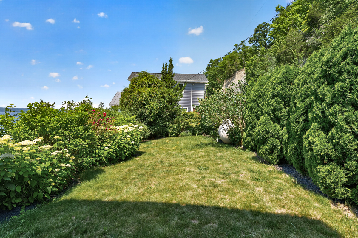 Side yard bordered by shrubs and trees