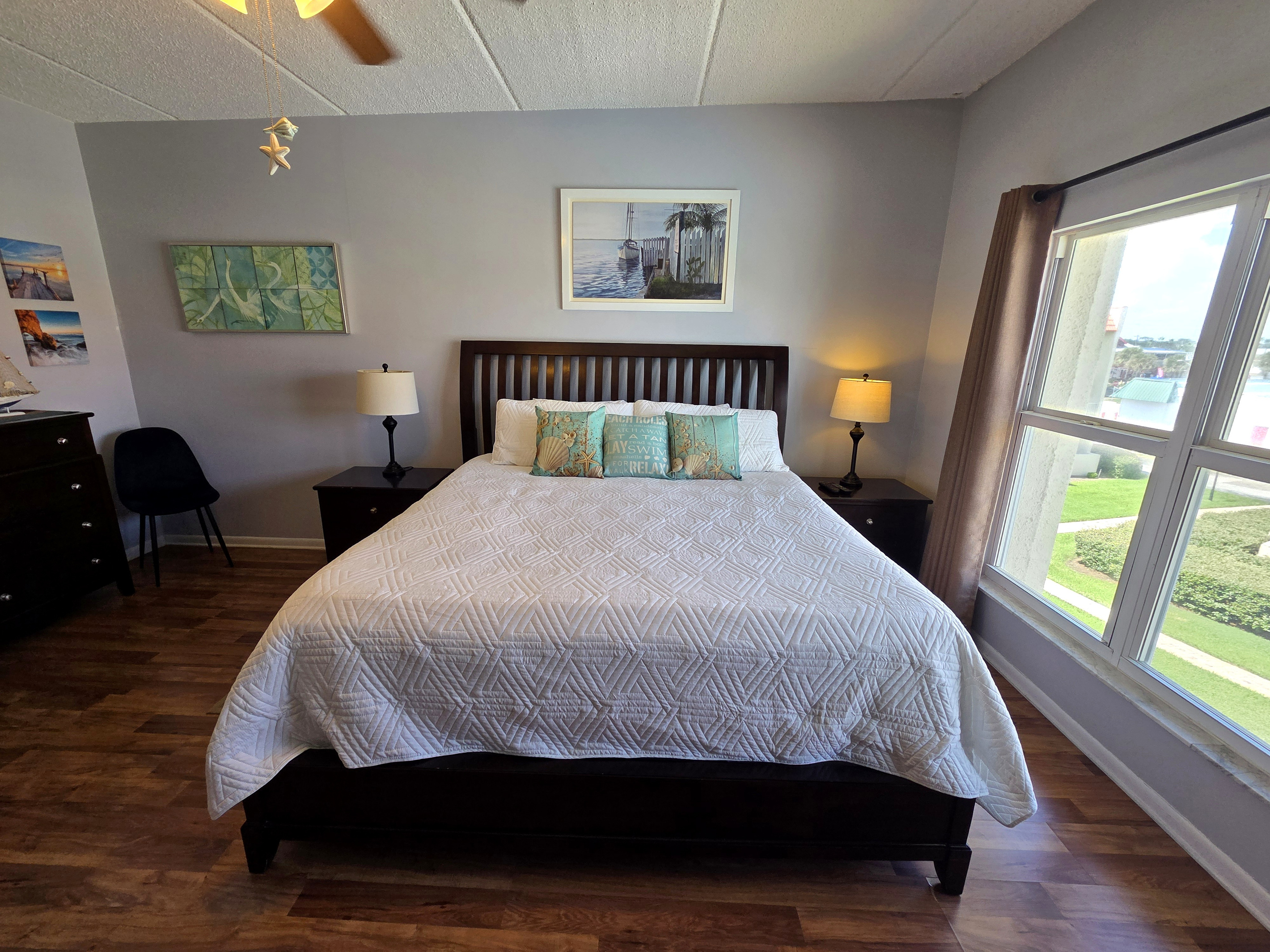 Relax in a bright king bedroom with coastal decor and views of lush grounds.