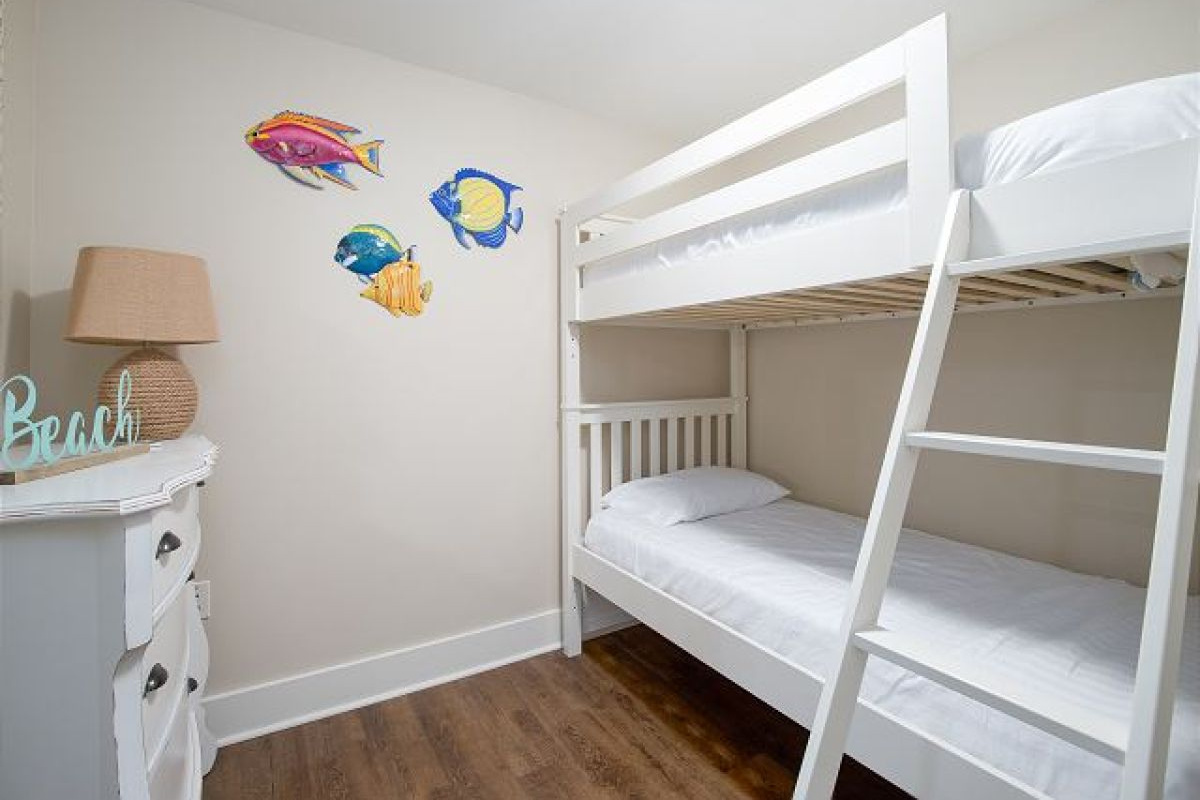 Second bedroom with twin-over-twin bunk bed, dresser, lamp and tropical fish wall art