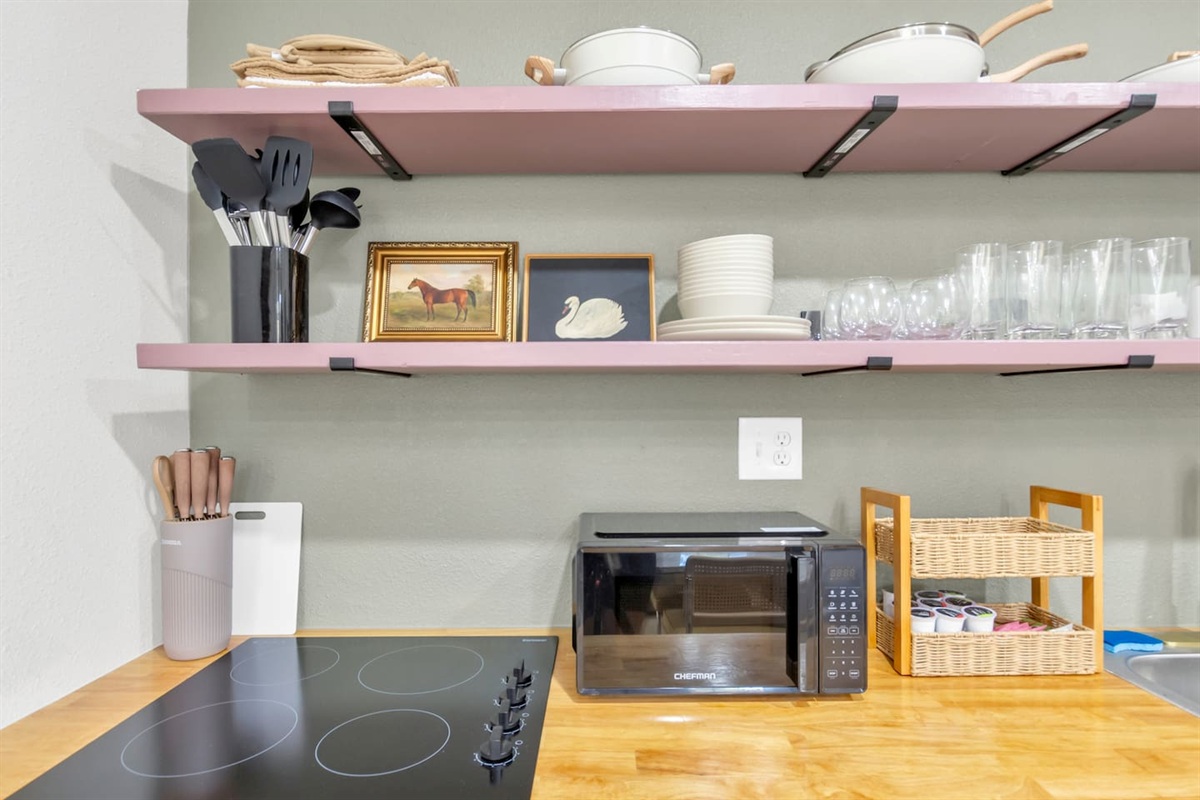 Cook with ease in this fully stocked kitchen featuring a 4-burner electric stove, oven, microwave, Keurig with pods, glassware, and all your cooking essentials.