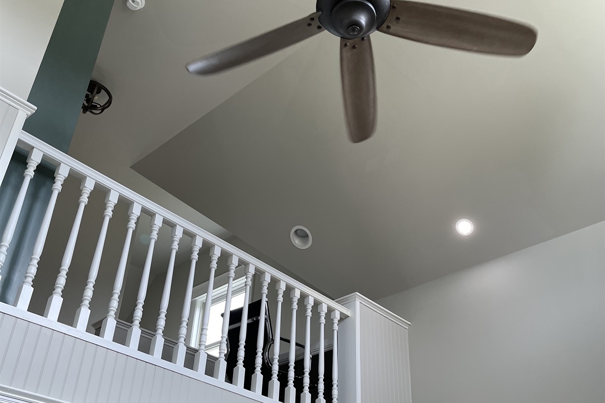 Loft over looking living area with large ceiling fan.  Desk on loft.