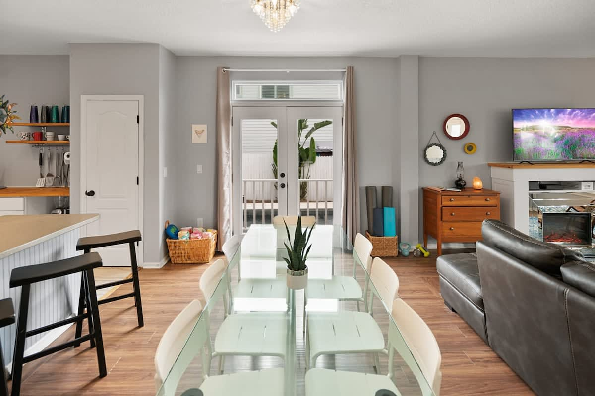 The open plan runs from kitchen through dining to living room. Whoever is cooking stays part of the conversation, and whoever is supposedly helping can keep half an eye on the pool through the windows.