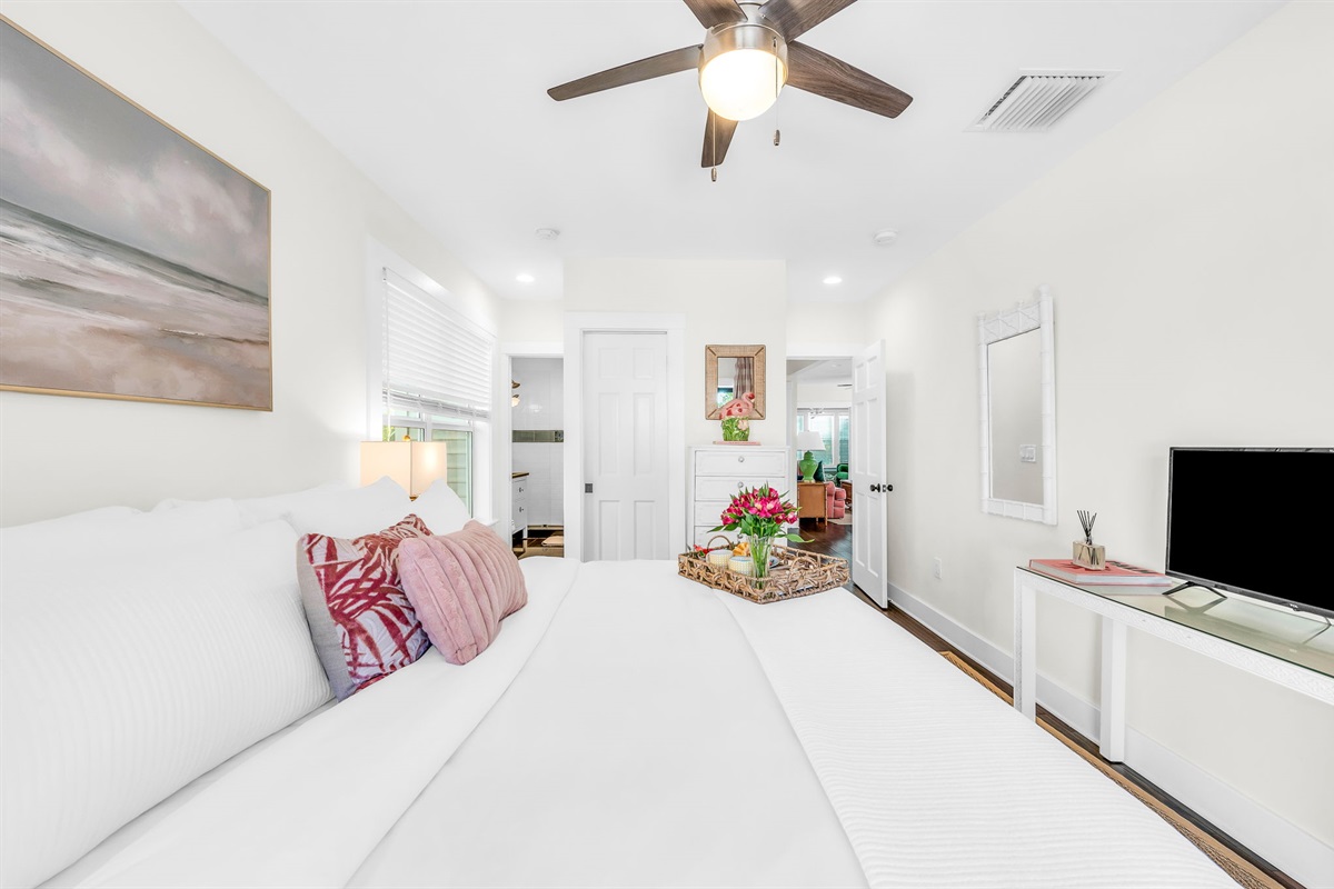 Serene king primary suite featuring a smart TV, private en-suite bathroom, and elegant French doors that open directly to the pool—perfect for seamless indoor-outdoor living and relaxing mornings or evenings.