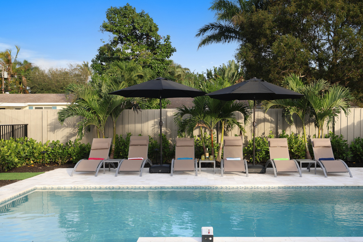 Your Delray Beach getaway includes a private pool, shaded loungers, lush palms, and a relaxed backyard setting made for downtime.