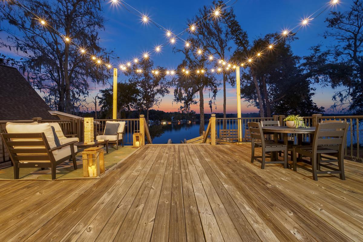 Sunset on the lakeside deck, string lights, lounge seating, dining for 4